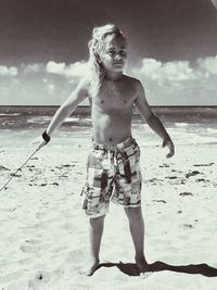 Full length of shirtless boy standing at beach