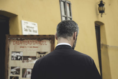 Rear view of man looking through window