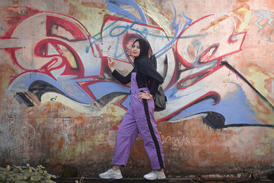 Full length of man standing against graffiti wall