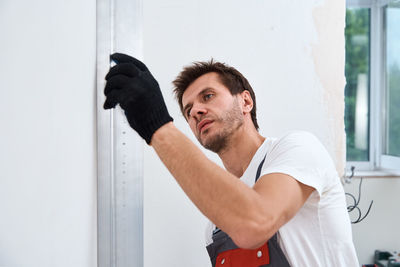 Portrait of young man standing against white wall