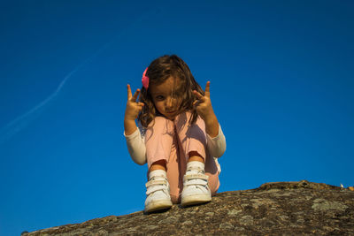 Low angle view of girl against blue sky
