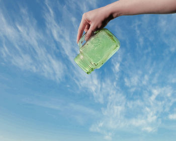 Low angle view of person holding ice cream against sky