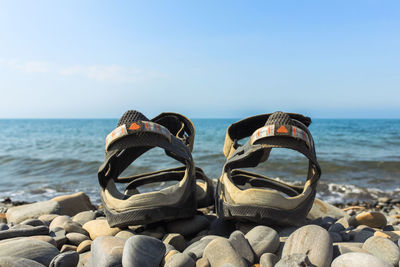 Lounge chairs on rocks by sea against sky