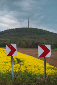 Road sign on field against sky
