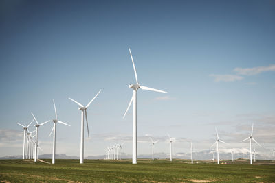 Wind turbines on field against blue sky