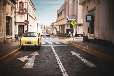 Cars on road by buildings in city