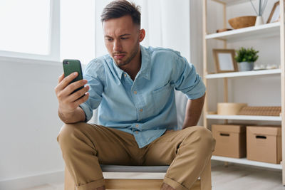 Young man using mobile phone while sitting at home