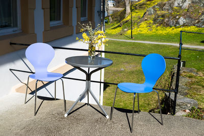 Flower vase on table amidst chairs on sunny day