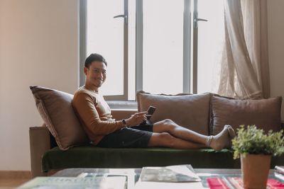 Side view of young woman sitting on sofa at home