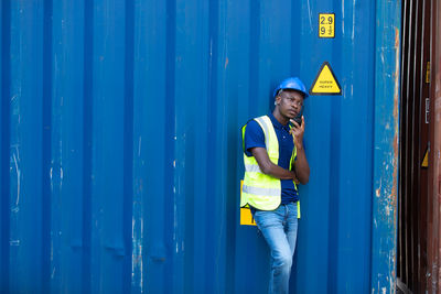 Young man standing against blue wall