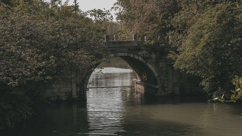 Arch bridge over river against trees