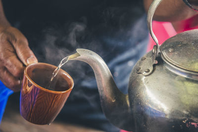 Close-up of hand pouring tea cup