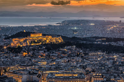 Aerial view of illuminated cityscape against sky during sunset