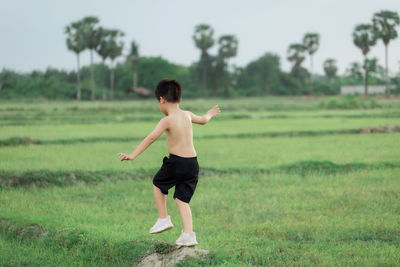 Rear view of shirtless man standing on field