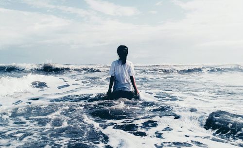 Rear view of man on sea against sky