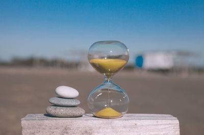 Close-up of wine glass on sand at beach against sky