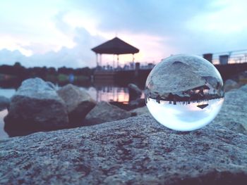 Close-up of crystal ball on rock against sky