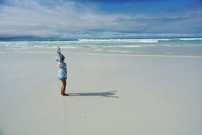 Full length of boy standing on sand at beach against sky