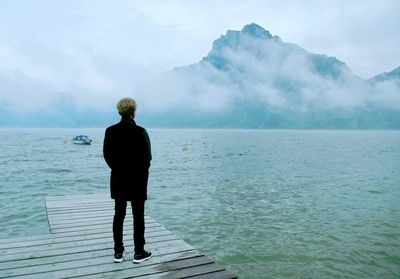 Rear view of man standing on jetty over sea