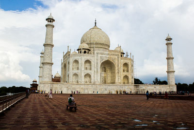 People in front of historical building against cloudy sky