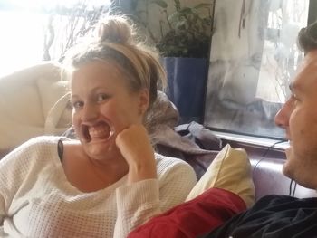 Close-up of smiling young woman sitting on bed at home