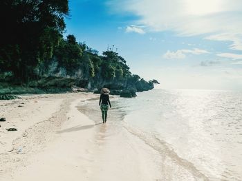 Rear view of woman on beach against sky