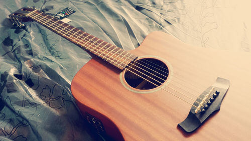 Close-up of guitar on bed