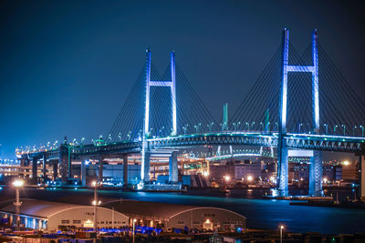 Illuminated bridge over river at night