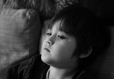 Close-up of boy leaning on sofa