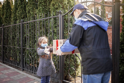 Girl receiving parcel from delivery person outdoors