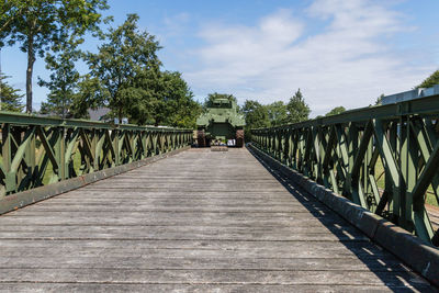 Footbridge amidst trees against sky