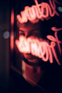 Thoughtful woman seen through illuminated sign on glass window