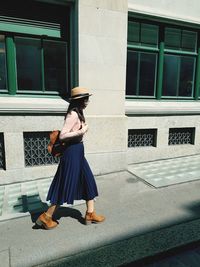 Woman walking on footpath by building