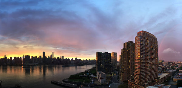 Panoramic view of cityscape by east river against cloudy sky during sunset