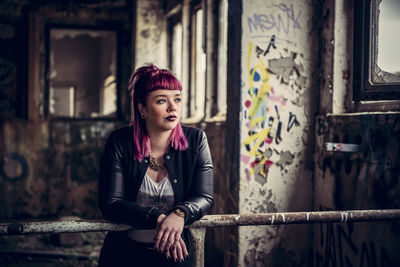 Young woman standing against wall