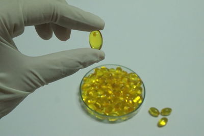 Close-up of hand holding yellow over white background