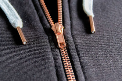 Copper colored fashion zipper in close-up macro view showing black sweatshirt with opened zipper