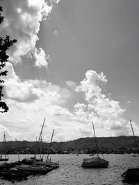 Sailboats moored in sea against sky