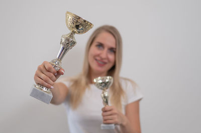 Cropped hand of man holding trophy against white background