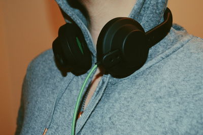 Midsection of man wearing headphones against brown background