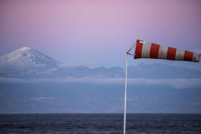 Windsock by sea against sky during sunset