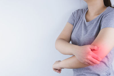 Midsection of woman sitting against white background