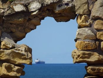 Rock formation by sea against clear sky
