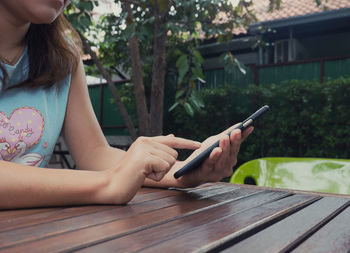 Midsection of woman using mobile phone over table