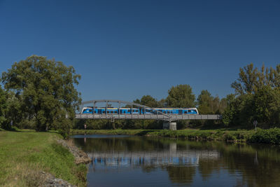 Arch bridge over river against clear blue sky