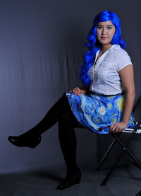 Portrait of woman sitting against wall