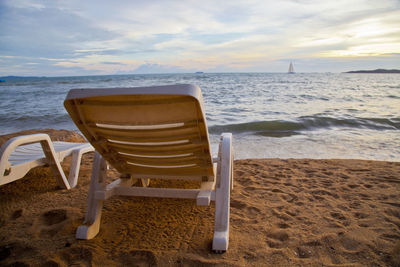 Chairs on beach against sky during sunset