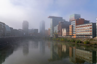 River by buildings against sky in city