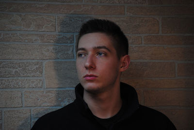 Young man looking away against wall