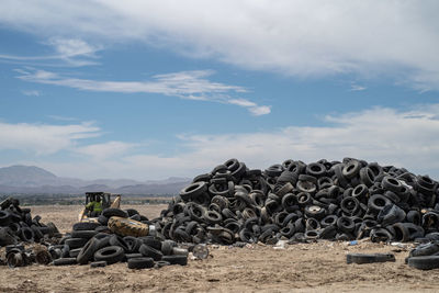 Stack of logs on field against sky